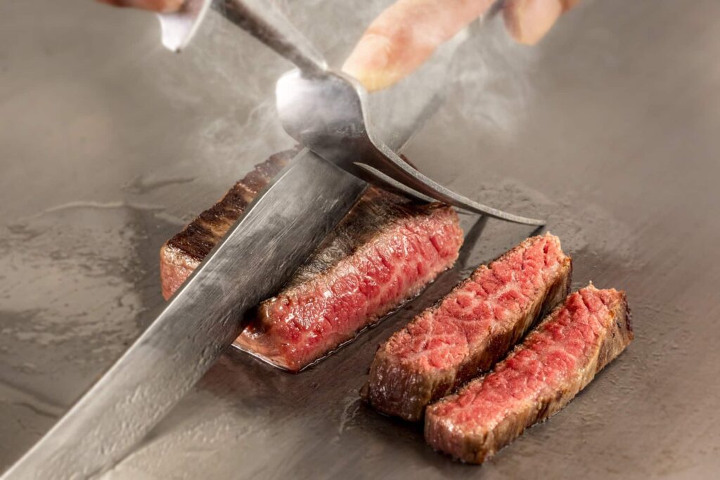 鉄板で焼いたランプステーキをナイフでカットする様子