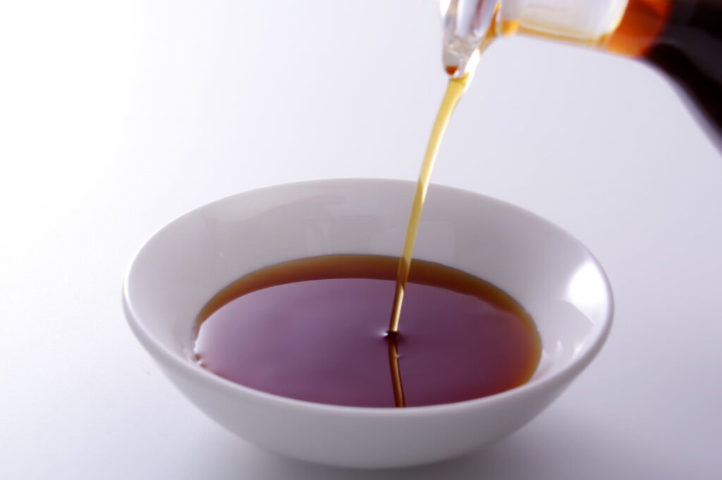 小皿に淡い色のうすくち醤油を注ぐ写真