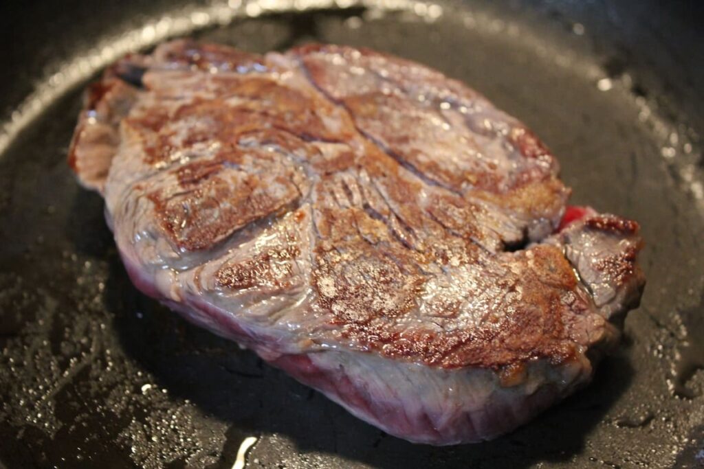 鉄板で肩ロースステーキを焼いている様子（焼き目がついた状態）