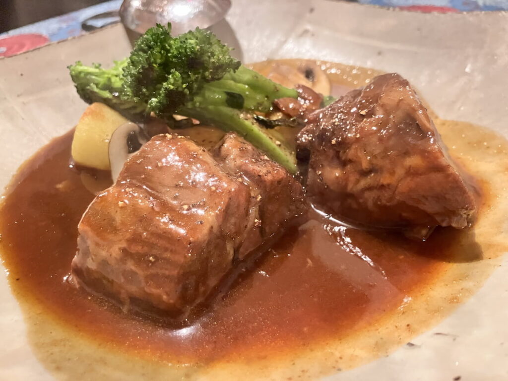 牛すね肉の煮込み料理の皿盛り。野菜と一緒に煮込まれた様子