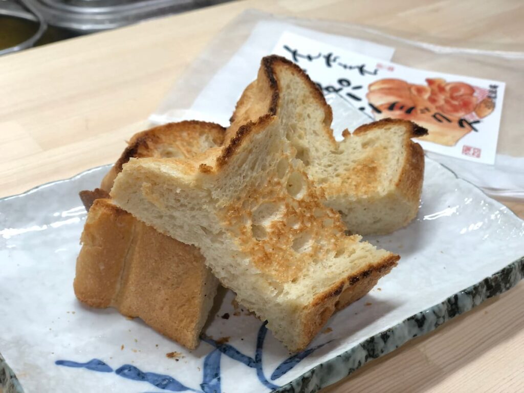 魔法庵のもちもち食パンミックスで作ったトーストを皿に並べた写真（パッケージ付き）