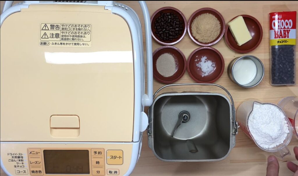 家庭用ホームベーカリーと材料を並べ、焼成前に検討している様子