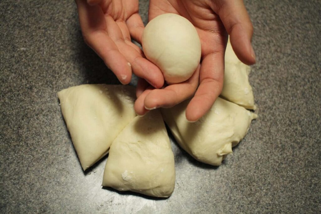 パン生地を手で丸めて成形している様子
