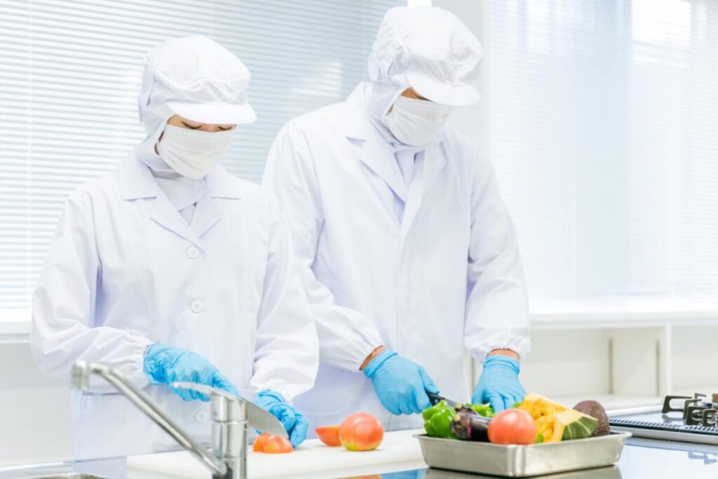 衛生管理された食品加工現場での野菜の下処理作業｜Oisixの安全性を示すイメージ
