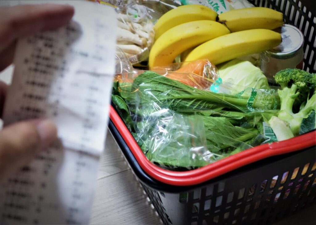 買い物かごいっぱいの野菜とレシートのイメージ写真