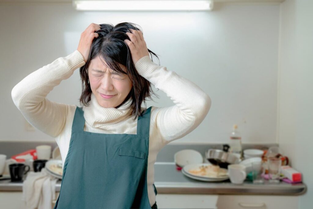 洗い物がたまり困っている女性のキッチンの様子