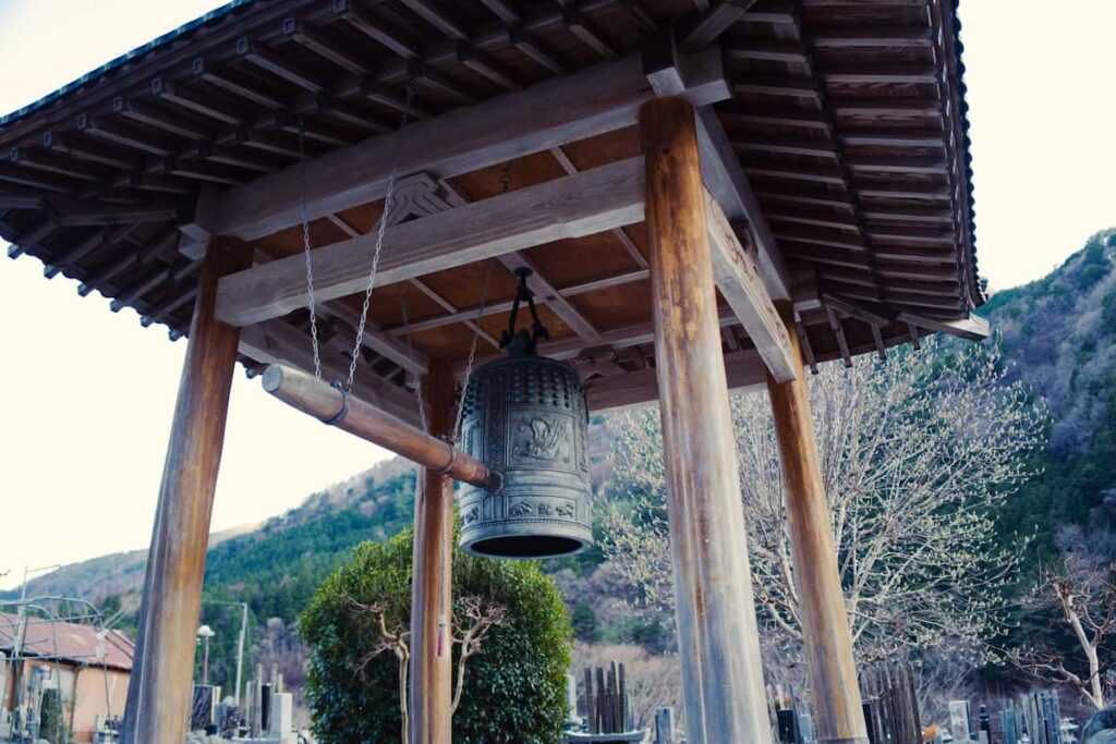 冬の山々を背景にしたお寺の大きな鐘（梵鐘）