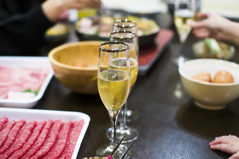 誕生日を祝う食卓にすき焼きとワインが並ぶ画像