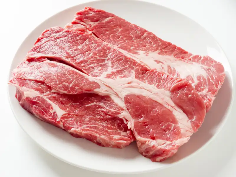 白い丸皿に盛り付けられた赤身と脂身のバランスが良いすき焼き用の肩ロース