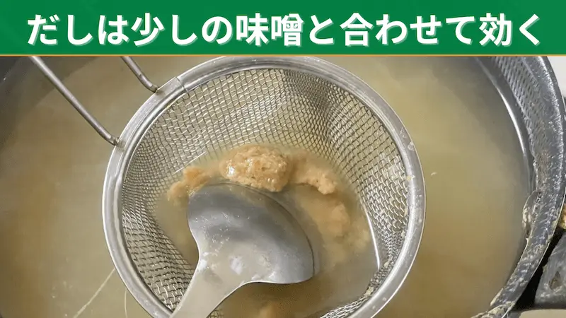 だしの鍋に、味噌こしで少量の味噌を溶いているところ